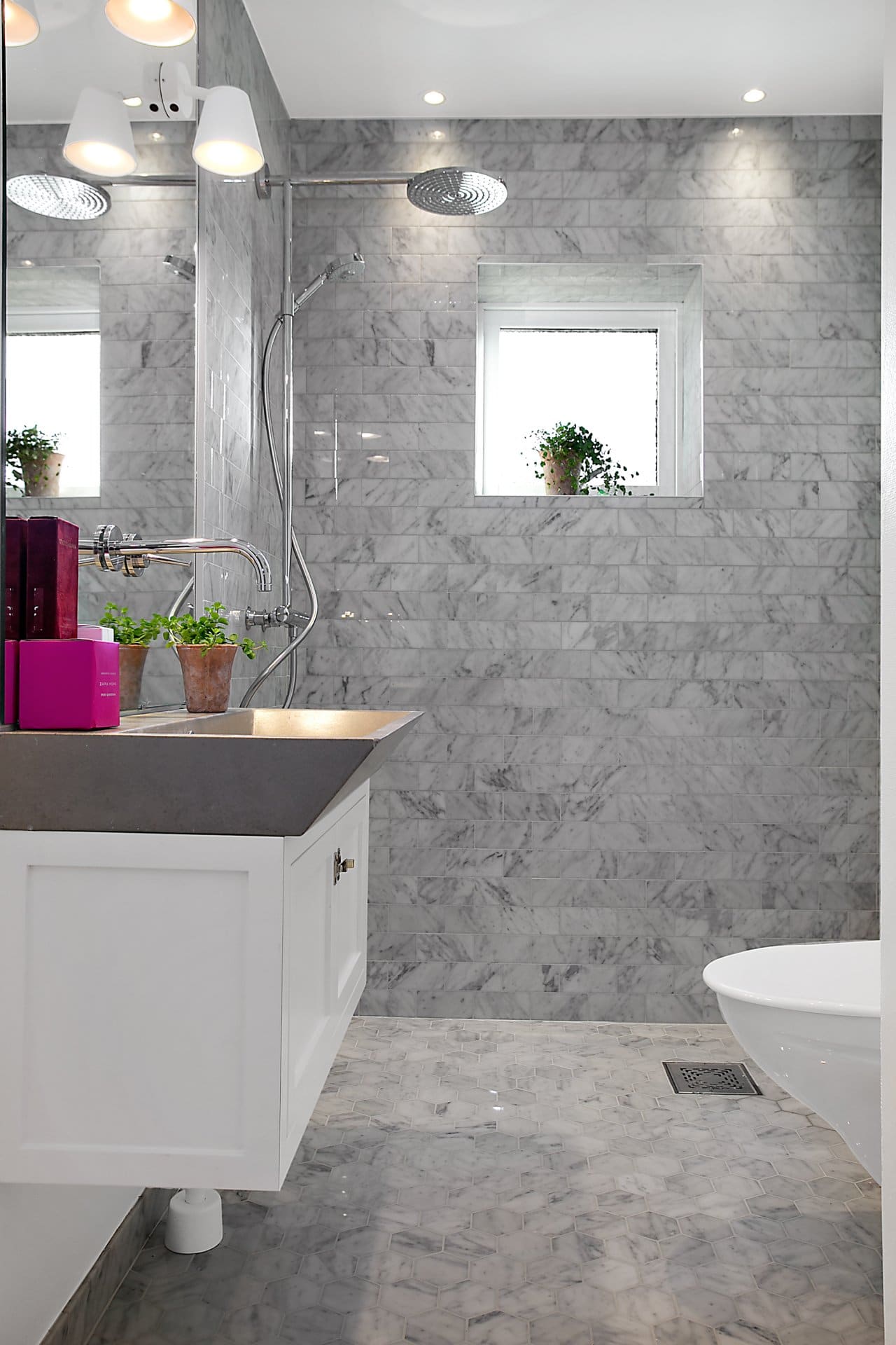 Stiligt - Ett badrum med carrara marmorväggar och en vit toalett.