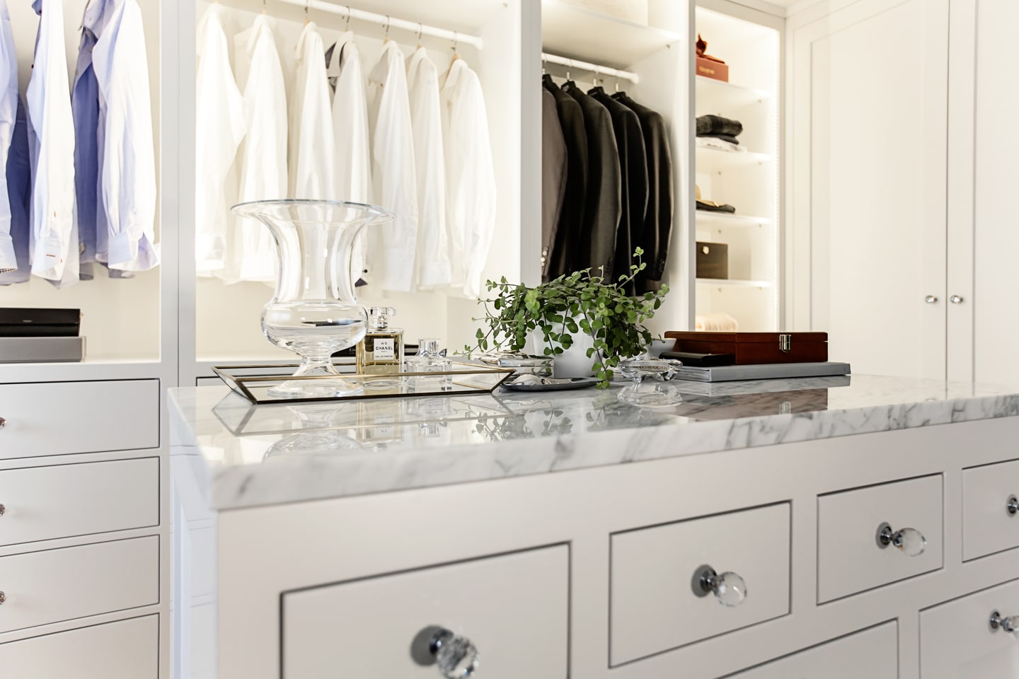 Stiligt - En vit walk in closet med en marmorskiva.