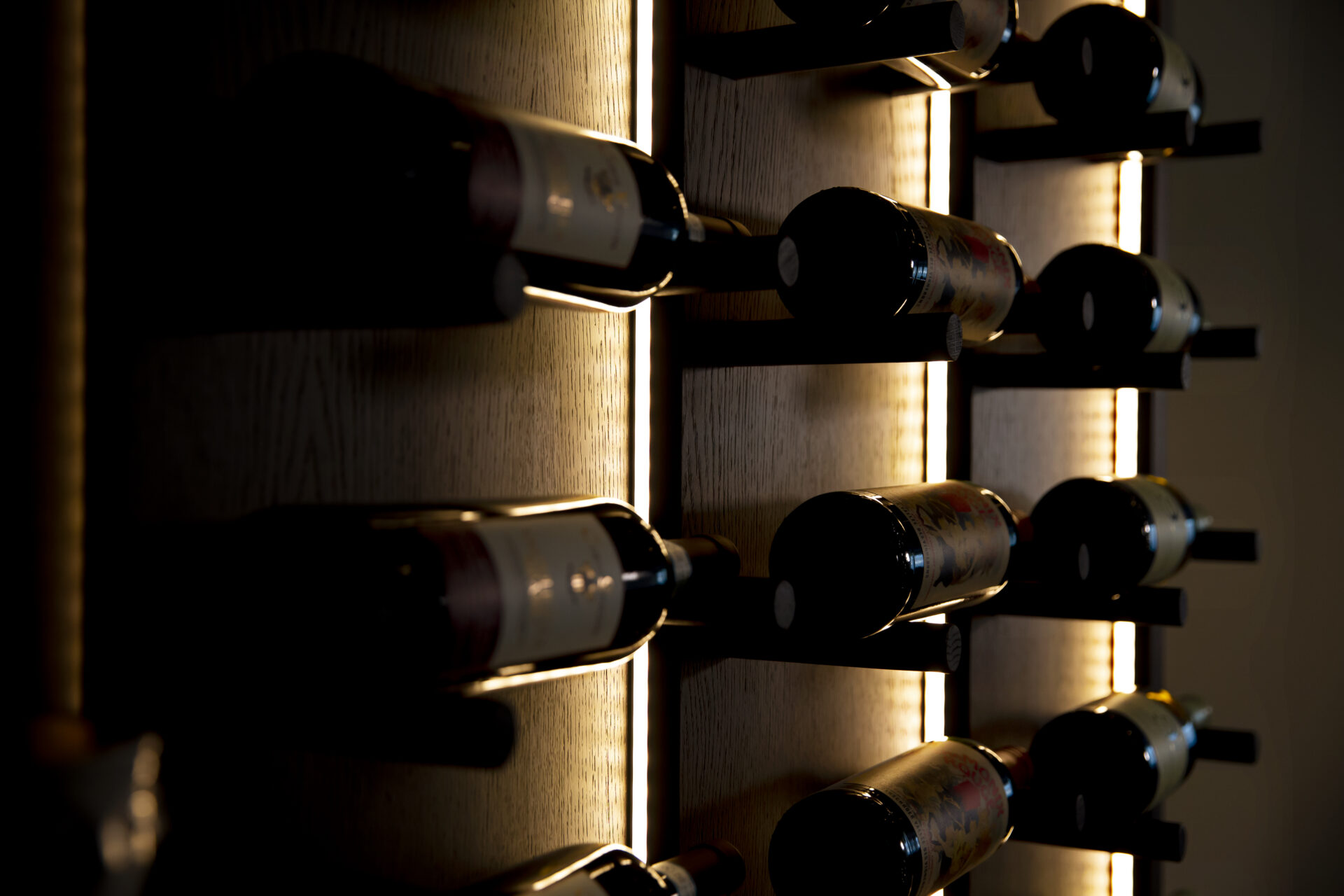 Stiligt - Ett vinställ i ett mörkt rum fyllt med många flaskor vin.