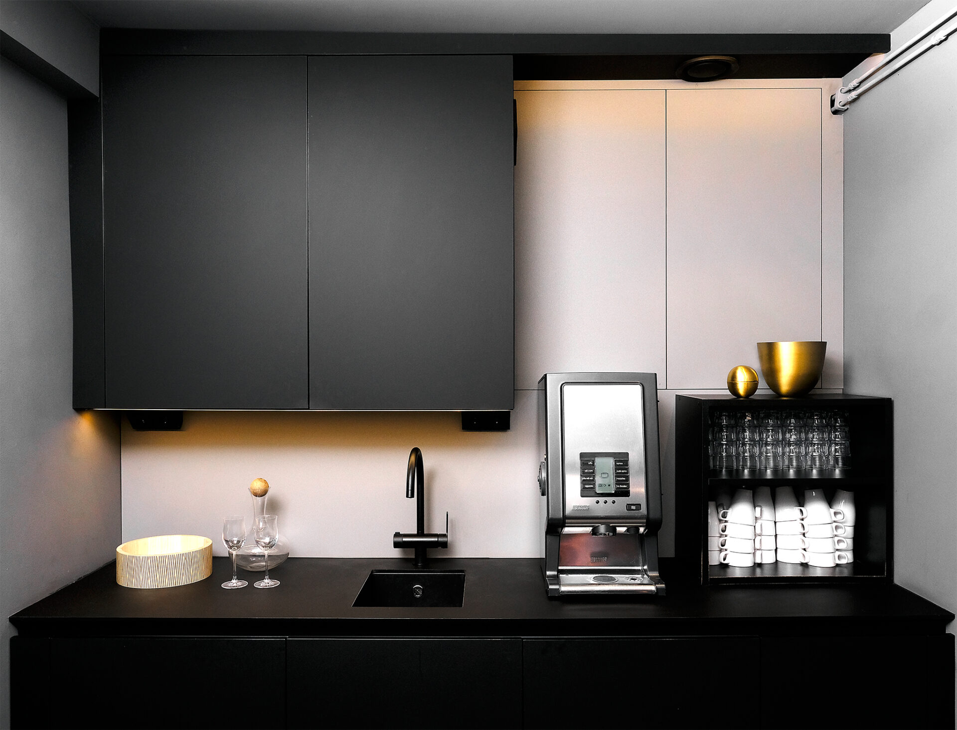 Stiligt - Ett litet modernt kök med svarta skåp och kaffebryggare.