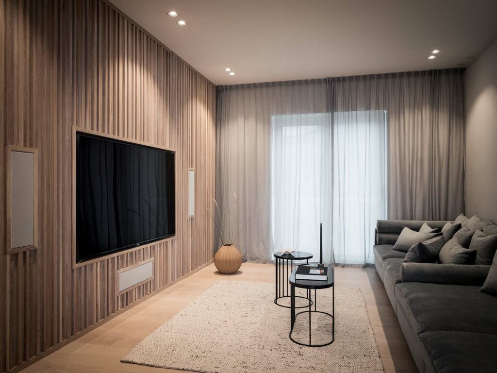 Stiligt - Ett vardagsrum med träväggar och en platt-TV, med ett unikt specialbyggt kök och klädkammare.