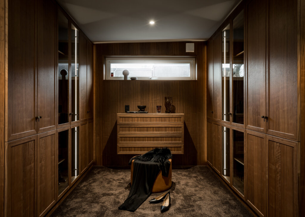 Stiligt - En platsbyggd walk in closet med träskåp och en svart sko.