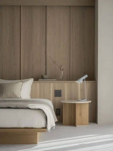 Stiligt - Ett sovrum med vit säng och träpanel designad inredningsdesign.