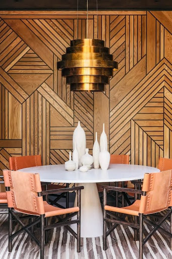 Stiligt - En matsal med en trävägg och ljusa orangea stolar, med elegant inredningsdesign.
